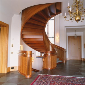 Ellipsformad trappa i körsbär, med kantstkodd gångmatta. Handledare och vangstycken böjlimmade till ett stycke-